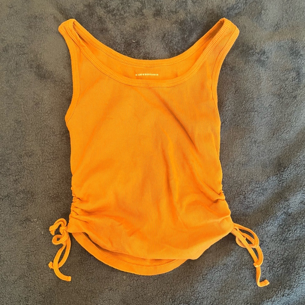 Muted orange colored ribbed tank top with strings on the sides to adjust crop.
